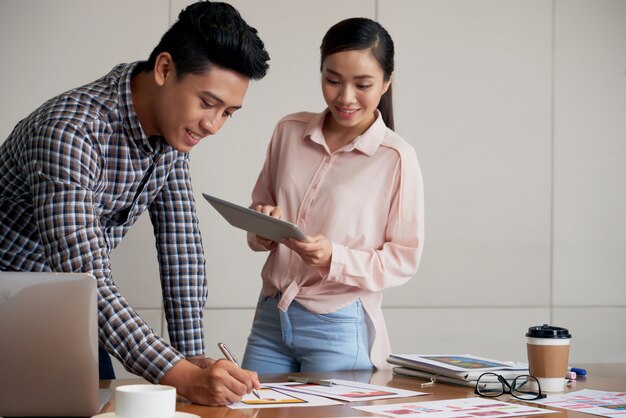 Mittlerer Schuss von den jungen asiatischen Leuten, die auf einem Startprojekt coworking sind