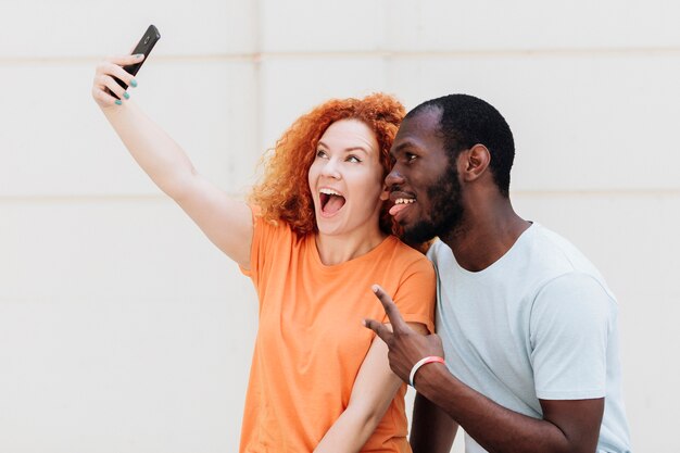 Mittlerer Schuss von den zwischen verschiedenen Rassen Paaren, die ein selfie nehmen