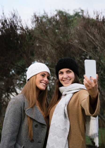 Mittlerer Schuss zwei lächelnde Frauen, die ein selfie nehmen
