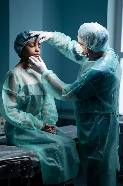 Kostenloses Foto mittlerer schussarzt, der den patienten vor der operation überprüft