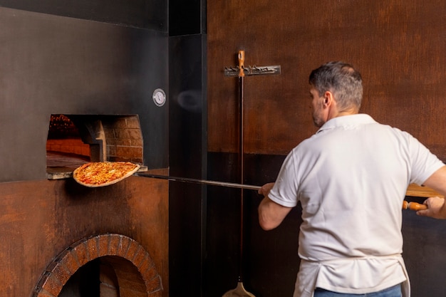 Kostenloses Foto mittlerer schußchef, der pizza zubereitet