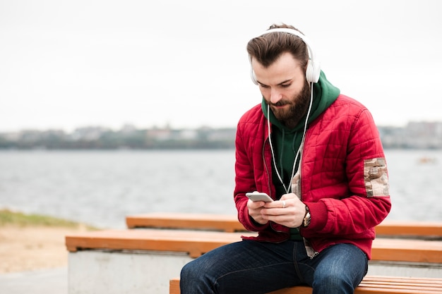 Kostenloses Foto mittlerer schusskerl, der seinen smartphone betrachtet