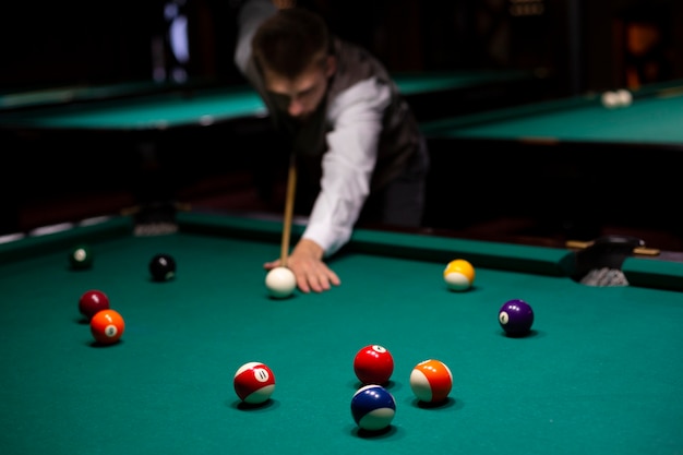 Mittlerer schusskerl mit dem poolstock, der billard spielt