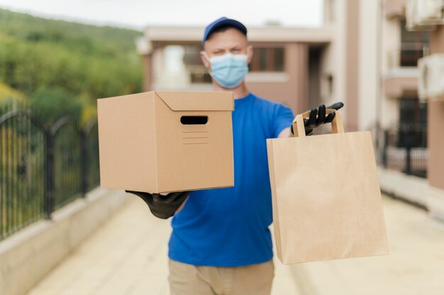 Mittlerer Schusslieferant, der Kasten und Tasche hält