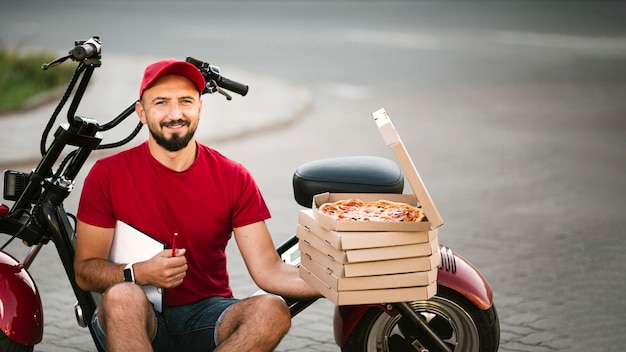 Kostenloses Foto mittlerer schusslieferer, der auf motorrad sitzt