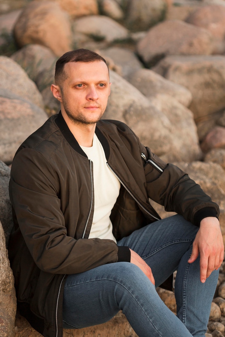 Kostenlose Foto mittlerer schussmann, der auf felsen sitzt
