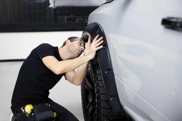 Kostenloses Foto mittlerer schussmann, der das rad des autos überprüft