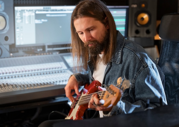 Mittlerer Schussmann, der die Gitarre im Studio spielt