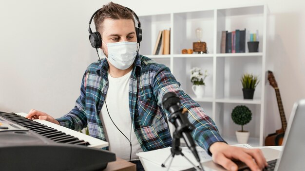 Kostenloses Foto mittlerer schussmann, der digitales klavier spielt