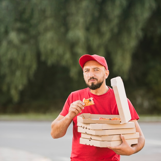 Mittlerer Schussmann, der draußen Pizza isst