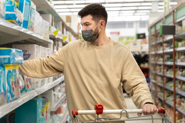 Mittlerer schussmann, der mit maske einkauft