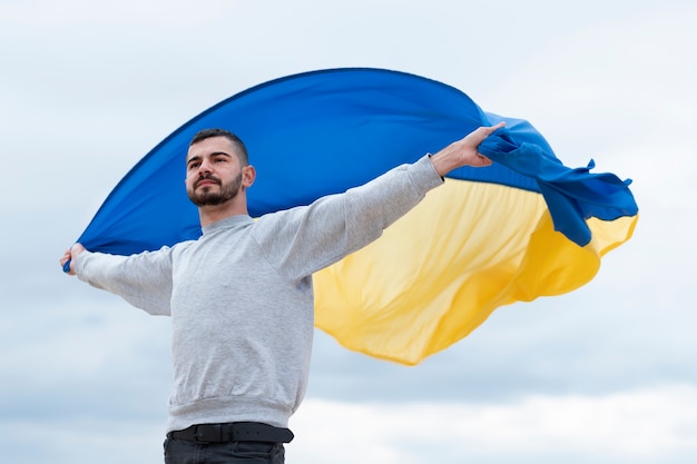 Mittlerer schussmann, der ukrainische flagge hält