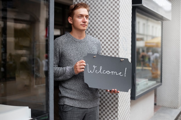 Kostenloses Foto mittlerer schussmann, der willkommensschild hält