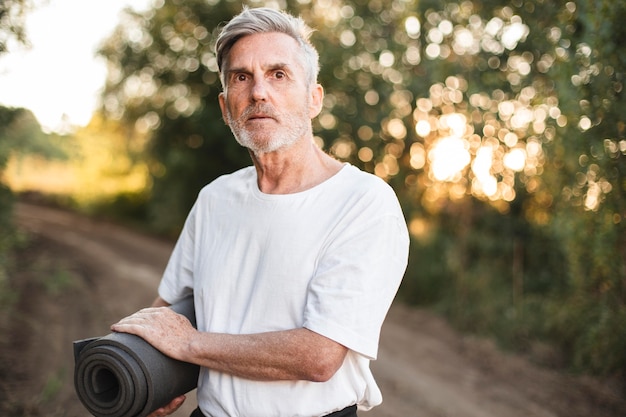 Kostenloses Foto mittlerer schussmann, der yogamatte hält