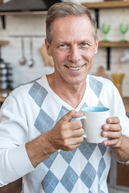 Mittlerer Schussmann mit Becher in der Küche