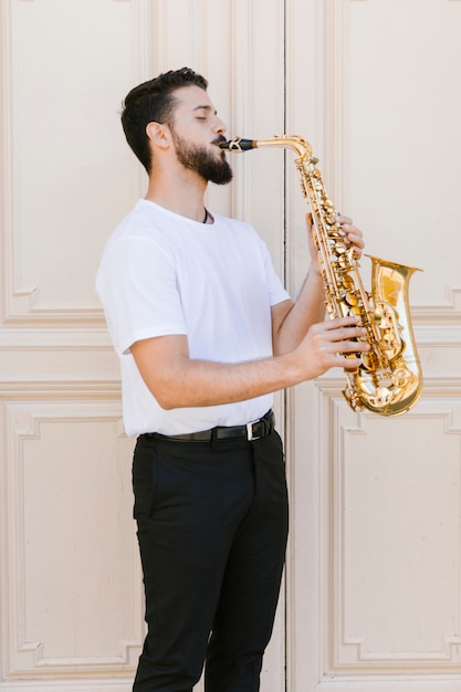 Kostenloses Foto mittlerer seitlicher musiker des schusses, der das saxophon spielt