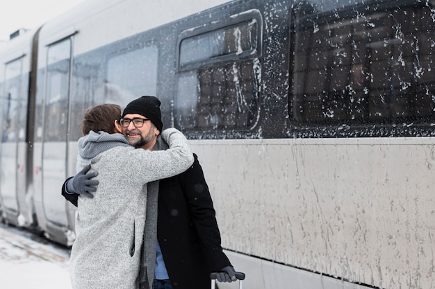 Mittleres glückliches Paar, das Winterzeit umarmt