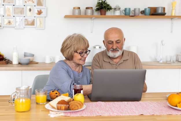 Mittleres Schuss älteres Paar, das mit Laptop sitzt