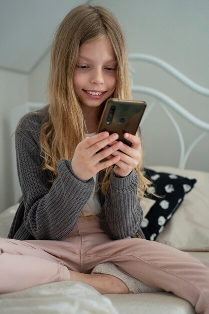 Mittleres Schuss Smiley-Mädchen mit Smartphone