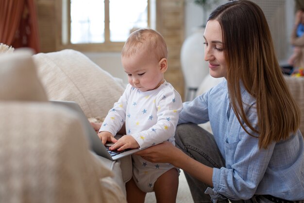 Mittleres Schußbaby, das auf Laptop schreibt