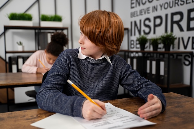 Kostenloses Foto mittleres schusskind, das beim schultest betrügt