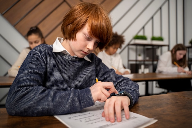 Kostenloses Foto mittleres schusskind, das beim schultest betrügt