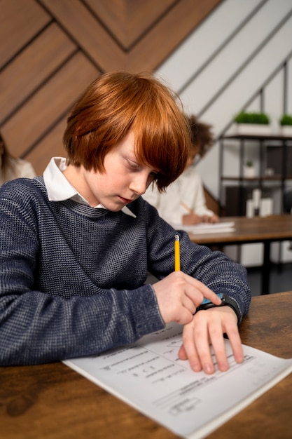 Kostenloses Foto mittleres schusskind, das beim schultest betrügt