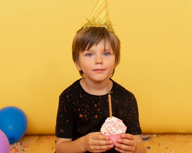 Mittleres Schusskind, das Cupcake mit Kerze hält