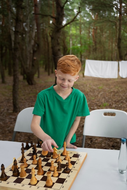 Kostenloses Foto mittleres schusskind, das draußen schach spielt