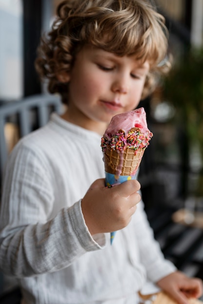 Kostenloses Foto mittleres schusskind, das eistüte hält