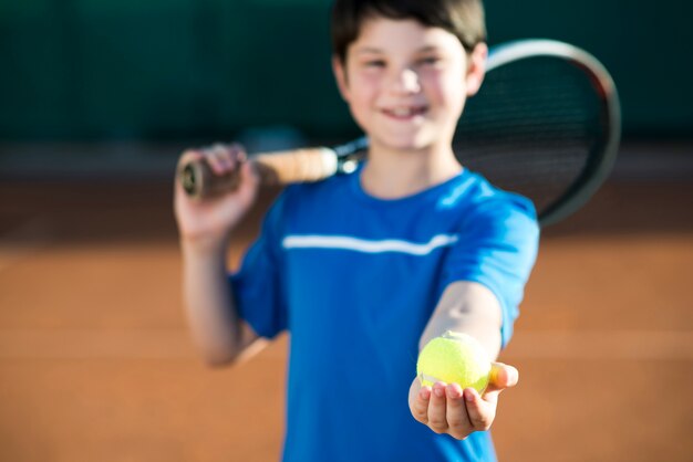 Mittleres Schusskind, das in der Hand einen Tennisball hält