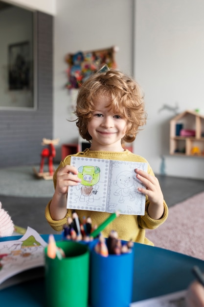 Kostenloses Foto mittleres schusskind, das malbuch hält