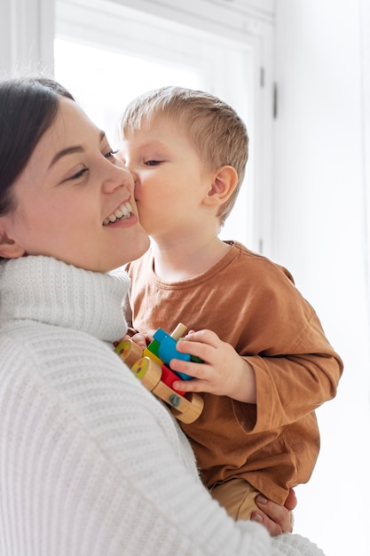 Kostenloses Foto mittleres schusskind, das mutter auf wange küsst