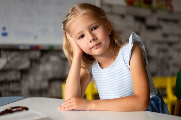 Kostenloses Foto mittleres schussmädchen, das am tisch sitzt