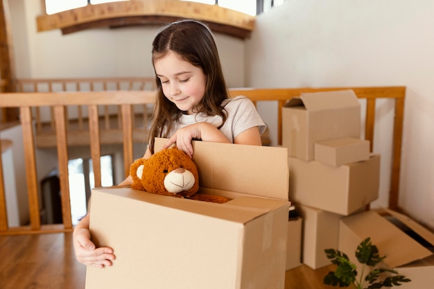 Mittleres Schussmädchen, das Kasten mit Spielzeug hält