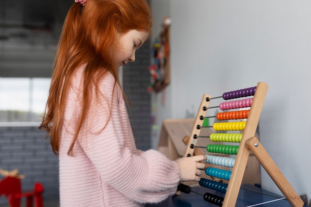 Kostenloses Foto mittleres schussmädchen, das mit holzspielzeug spielt