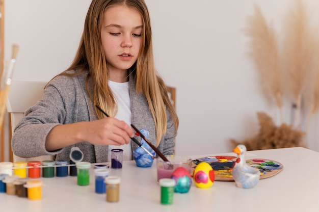 Kostenloses Foto mittleres schussmädchen, das pinsel hält