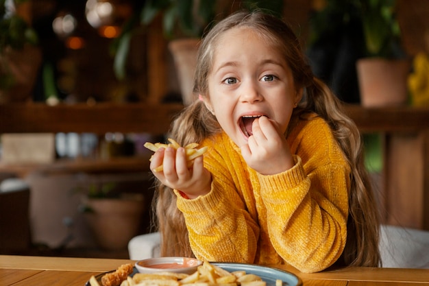 Kostenloses Foto mittleres schussmädchen, das pommes frites isst