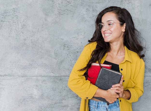 Kostenloses Foto mittleres schussmädchen mit büchern und zementhintergrund