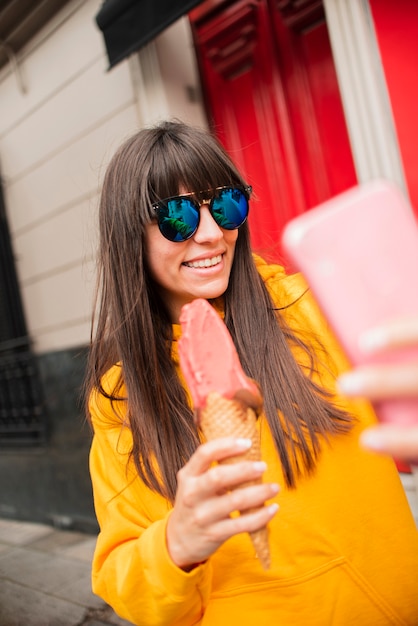 Mittleres Schussmädchen mit der Eiscreme, die selfie nimmt