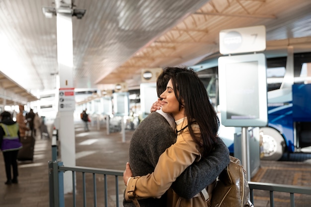 Kostenloses Foto mittleres schusspaar, das sich am flughafen umarmt