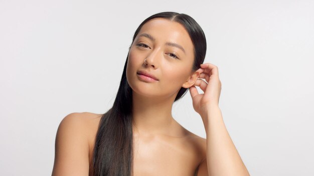 Mixed-Race-Model berührt ihr Haar und beobachtet die leuchtende, natürliche, ideale Haut der Kamera