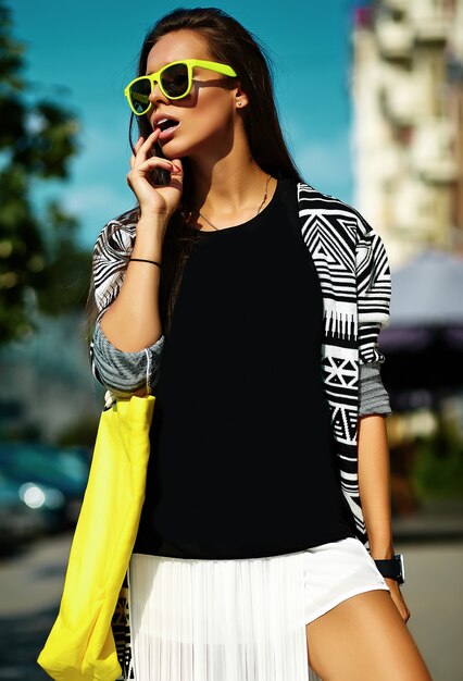 Mode stilvolle schöne junge Brünette Frau Modell im Sommer Hipster bunte Freizeitkleidung posiert auf Straße Hintergrund