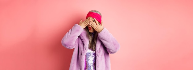 Kostenloses Foto mode- und einkaufskonzept stilvolle asiatische hipster-oma in lila outfit, die ihre augen bedeckt