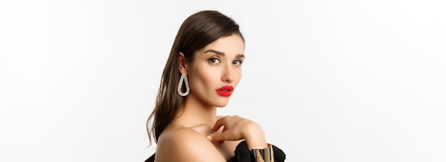 Mode- und Schönheitskonzept, Nahaufnahme einer eleganten Frau mit rotem Lippen-Make-up und Ohrringen, die auf die Kamera blickt