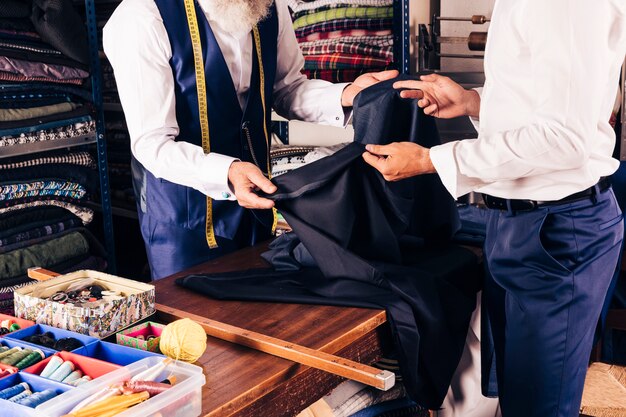 Modedesigner, der seinem Kunden Gewebe im Shop zeigt