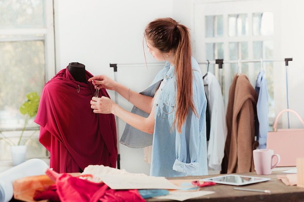 Modedesignerin, die im Studio arbeitet, sitzt auf dem Schreibtisch