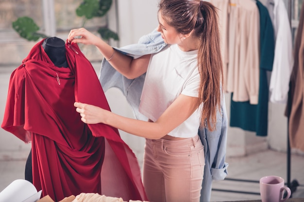 Modedesignerin, die im Studio arbeitet, sitzt auf dem Schreibtisch