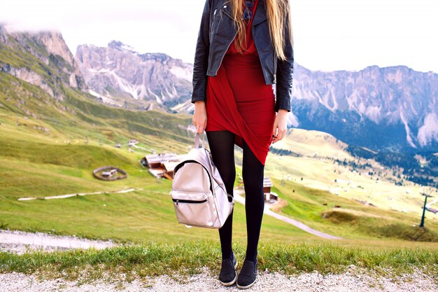 Modedetails der stilvollen Touristenfrau, die das Essen der eleganten Lederjacke des Kleides und des trendigen Rucksacks aufwirft, modischer Luxusurlaub in den Alpenbergen.