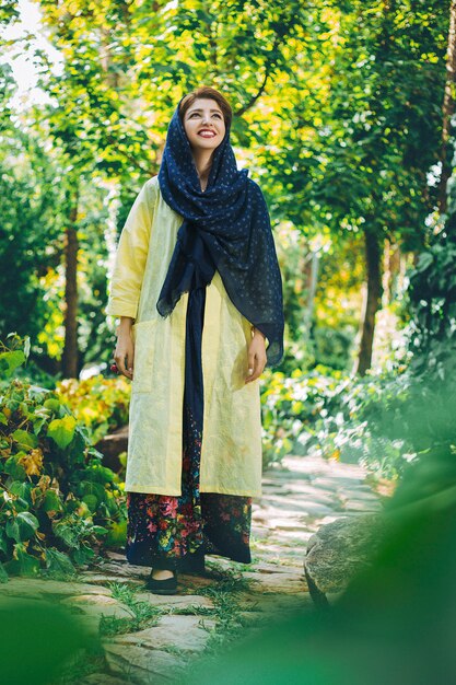 Model im beigen Kleid mit Kopftuch in der Natur